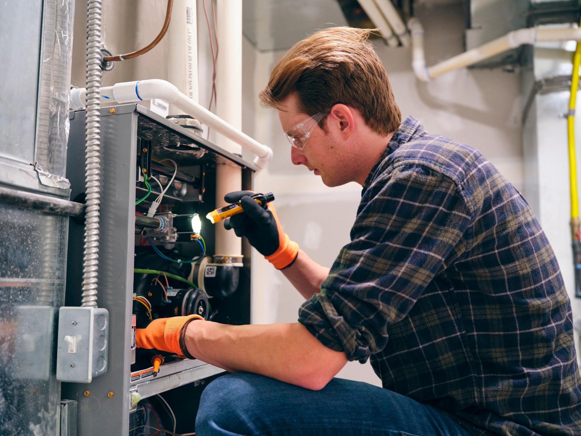 HVAC technician working on a furnace during a service call